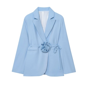 Détail d'un blazer bleu clair avec une grande fleur 3D et une ceinture à la taille