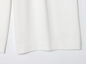 Détail de l'ourlet du pantalon blanc avec coutures précises et texture de tissu fluide