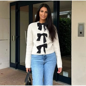 Cardigan bianco a costine con tre grandi fiocchi neri decorativi e stile alla moda