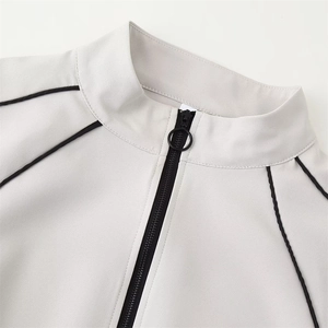 Détail de veste grise à col montant avec fermeture éclair à anneau et liseré noir fin