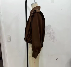 Detail view of the dark brown women jacket with structured shoulders and pleated straps