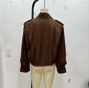 Detail of dark brown jacket back with inverted pleat design and buttoned cuffs