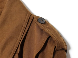 Detail of shoulder epaulette with button on brown twill fabric jacket for women