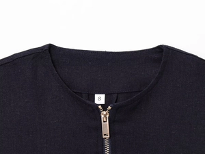 Detail of a black linen jacket collar with a sleek golden zipper and S size tag