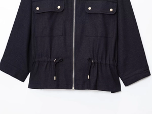 Detail view of linen jacket featuring golden metal buttons and adjustable drawstring waist
