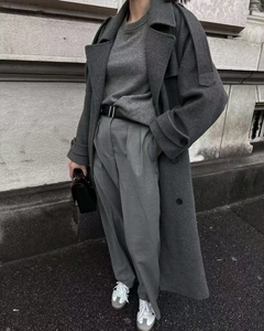 Detail view of a long dark grey wool coat with a black leather belt in a street style setting
