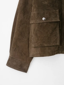 Detailed macro view of dark brown suede jacket with silver button on large flap pocket
