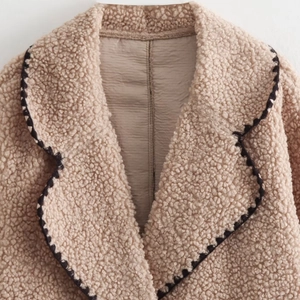 Chic beige faux shearling jacket featuring a large lapel and contrast wavy trim detailing