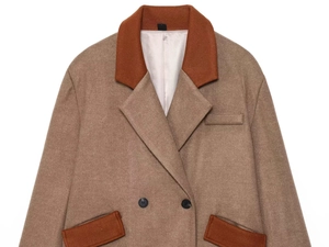 Detailed view of color-block wool coat featuring notch lapels and brown contrast pockets