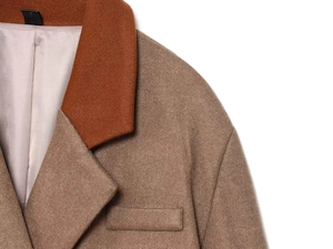 Detail of wool blend coat featuring contrast orange lapels and premium textured fabric