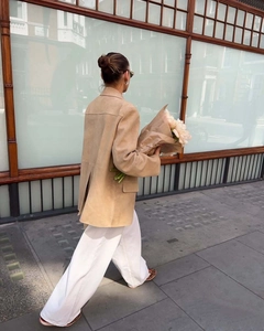 Outdoor street view of a beige suede jacket with back slit and straight-cut silhouette