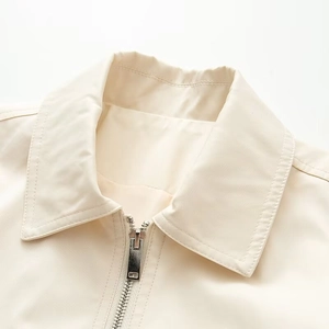 Detail of light beige jacket lapel showing smooth fabric texture and metal zipper