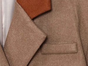 Detail of color-block lapel and premium wool texture on a brown tailored coat