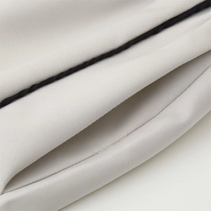 Vue détaillée du tissu sergé gris clair avec liseré contrasté noir sur le bord