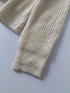 Dettaglio della manica del cardigan in maglia grossa color crema con polsini a coste