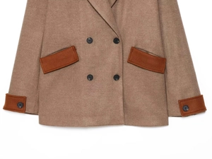 Detail of camel wool coat featuring orange contrast pockets and black double-breasted buttons