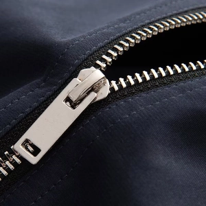 Close-up of silver metal zipper with long puller on durable dark navy jacket fabric