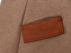 Macro detail of camel wool coat fabric showing premium texture and contrast stitching