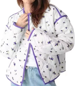 Detail of quilted white jacket featuring purple floral print and metal snap buttons