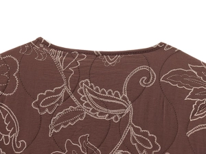 Détail de l'encolure ronde sur veste matelassée marron avec broderies paisley blanches