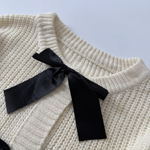 Elegante cardigan in maglia a nido d'ape color crema con fiocco in raso nero sul collo