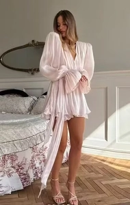 Détail d'une robe courte en satin avec décolleté en V, manches bouffantes et liens à nouer