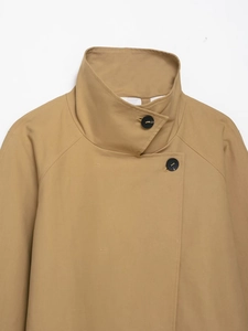 Detail of khaki jacket with funnel neck, raglan sleeves, and offset black button closure