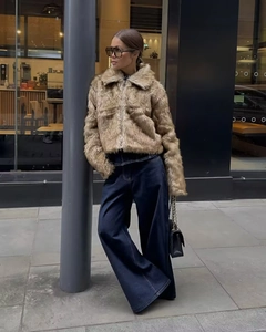 Detailed texture of brown faux fur jacket with metal zipper closure and plush finish