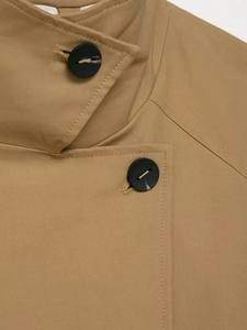 Detail of khaki jacket showing high-quality stitching and large black round buttons