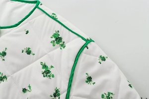 Macro view of green floral print on white quilted fabric with diamond stitching and green piping