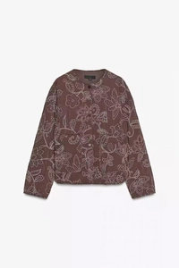 Close-up of floral embroidery on brown quilted jacket with snap button closure