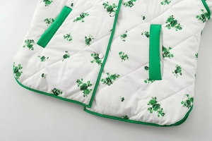 Detail of white quilted jacket with green floral print and silver snap button closure