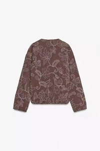 Close-up back view of brown quilted jacket featuring detailed white floral embroidery