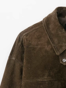 Détail d'une veste aviateur en daim marron foncé avec bouton métallique sur le col