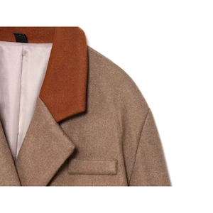 Close-up of a color-block wool coat with notch lapels in camel and rust brown tones