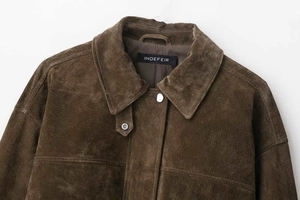 Détails du col en daim marron foncé et de la fermeture à bouton de la veste de pilote
