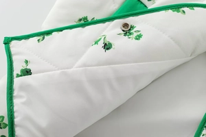 Close-up of diamond-quilted jacket with green plant print and metallic snap button