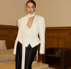 Detail of white V-neck blazer featuring a unique integrated scarf tie and structured fabric