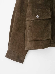 Détail du blouson aviateur en daim marron avec grandes poches à rabat et boucles en métal