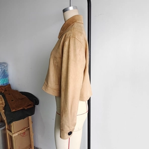 Detail showing the tan suede jacket texture with long sleeves and button cuffs