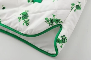 Close-up of diamond quilted fabric with green floral print and matching piped edges