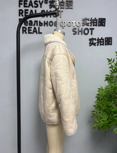 Detail view of a loose beige shearling jacket featuring soft faux suede and warm white wool lining