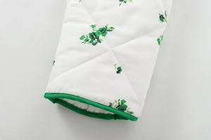 Detail of green floral print on white quilted cotton fabric with stitched diamond patterns
