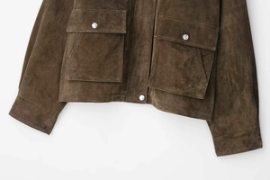 Détail d'une veste en daim marron montrant des poches à rabat et des boutons en métal