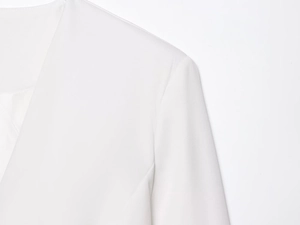 Close-up of white blazer showing high-quality textured twill fabric and refined stitching
