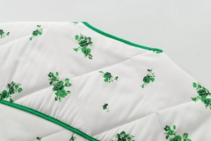 Close-up of quilted floral fabric with green trim and diamond stitching detail