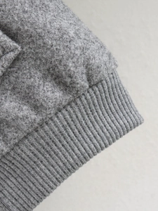 Détail de la veste bomber en tweed gris avec poignets en tricot côtelé et tissu texturé