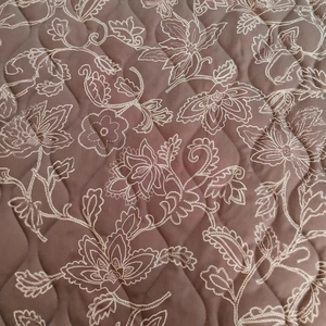 Deep brown quilted jacket with white floral embroidery and diamond stitching pattern