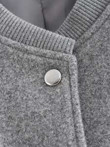 Détail d'un blouson bomber en tweed gris avec col en maille et bouton pression argenté