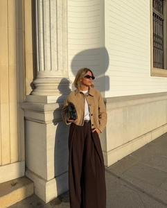 Close-up of a khaki suede jacket with large pockets on a model in an urban street setting